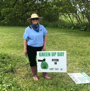 Carrie Spear spent her Memorial Day “day off” putting up a Green Up Day sign. She also spent the holiday hanging geraniums around the East Village. Photo by Chea Waters Evans