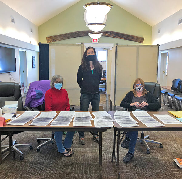 Volunteer Elaine Sharrow (feeling optimistic for spring in her flip flops), Assistant Town Clerk and Treasurer Sy Koerner, and volunteer Jules Polk had a busy day running the polls on Tuesday. Photo by Chea Waters Evans