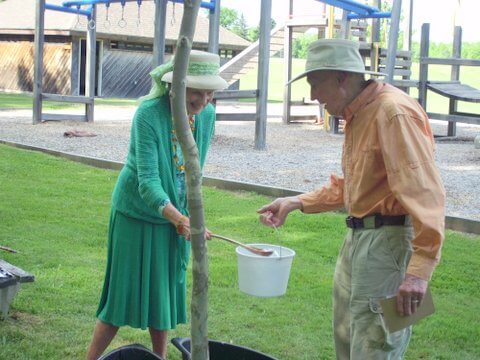 Alice Outwater and Larry Hamilton, in 2016, offered a water blessing to the newly planted trees at the Charlotte Beach playground. Photo by Linda Hamilton