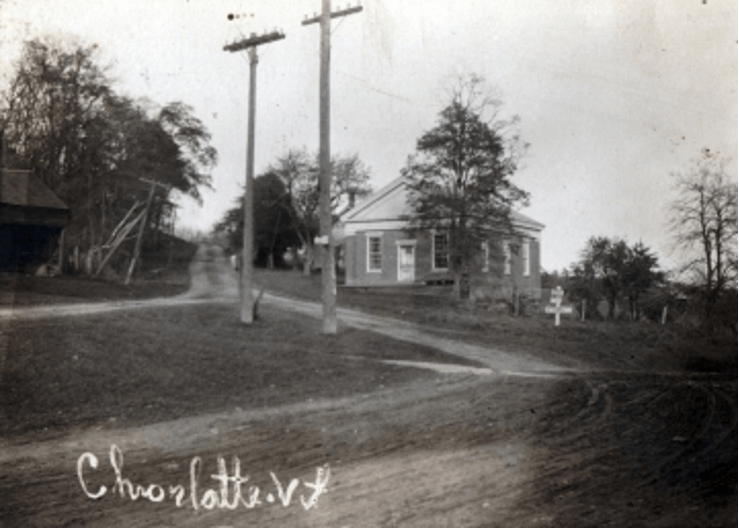 The Charlotte Museum (undated photo) showing the old Route 7 up the hill to the west of the building. Credit: “Look Around Hinesburg and Charlotte, Vermont” by Lilian Baker Carlisle, Chittenden County Historical Society, 1973