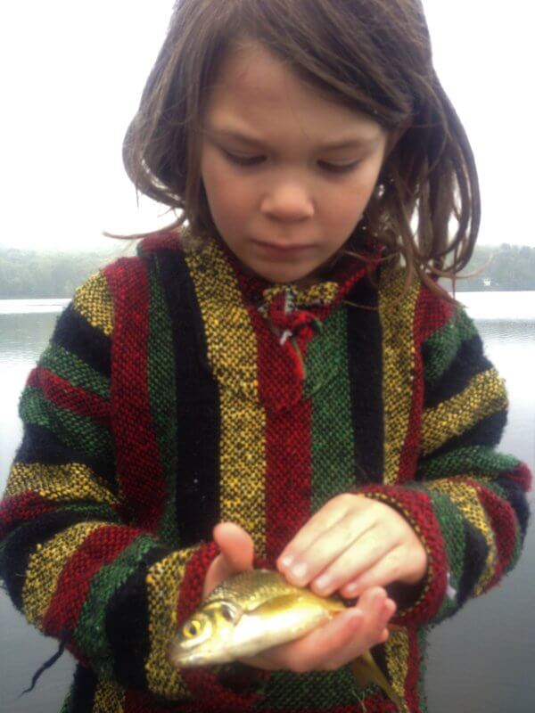 A young child admires the first fish they caught fishing. Photo by Bradley Carleton
