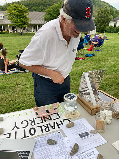 Above: The Charlotte Energy Committee focused on renewable energy at its table at the Grange on the Green concert on July 15, with a s’mores solar oven made by college-bound committee member Carolina Sicotte. Is Mike Yantachka going in for a marshmallow...or is that big smile because he loves solar power and the energy independence it gives communities?