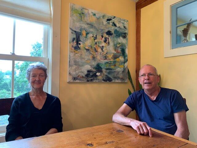 Jay and Marcia Vogler they are seated below a painting by Jay. Photo by Lucie Lehmann