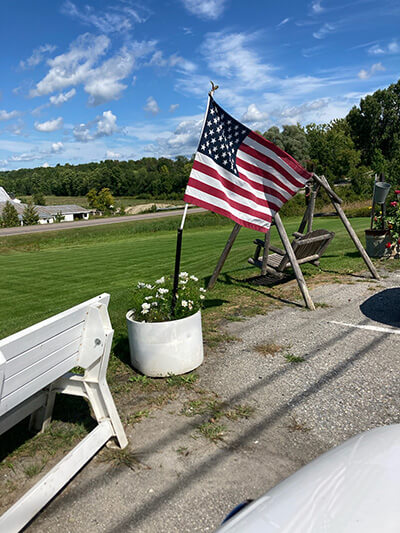 An American flag greets cyclists at the Kelly Brush Foundation event. The flag sits near Spear’s Corner Store. Photo by Gail Callahan