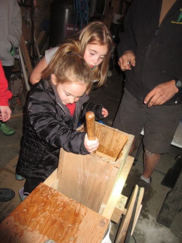 Sadie Moore (front) and Mia Paquette (behind) press the apples to make apple cider. Photo by Cindy Bradley