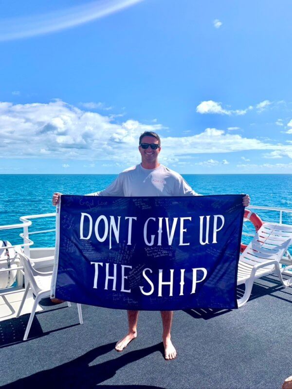 Courtesy photo Kyle Jaunich on a dive trip to the Bahamas. The ‘don’t give up the ship’ banner was signed by all of his doctors and nurses every time he went into a hospital. While at the Naval Academy, he did a semester at sea, so there are also pictures of him and the banner at places like the Great Wall of China and on Table Mountain in South Africa.