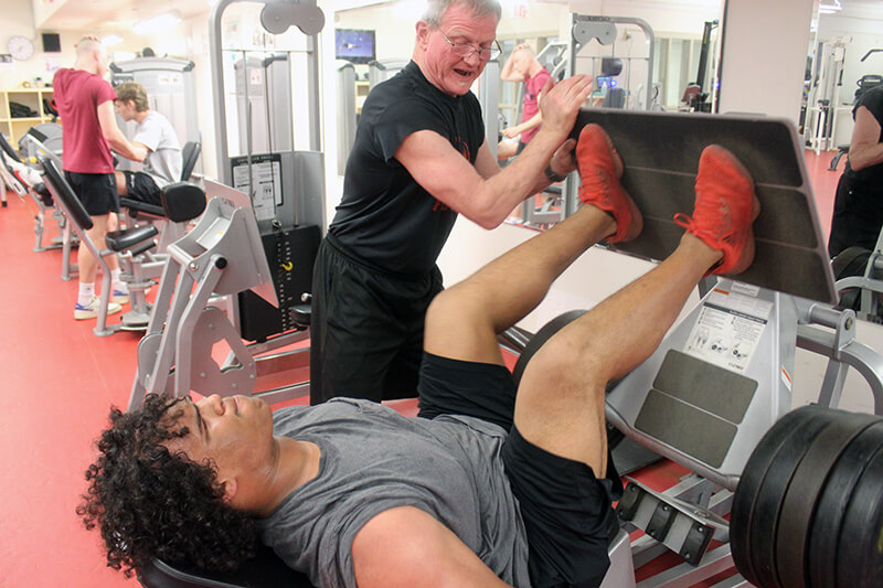 Kenyon Thompson of Hinesburg gets encouragement from Rahn Fleming as he works out on the hip press.