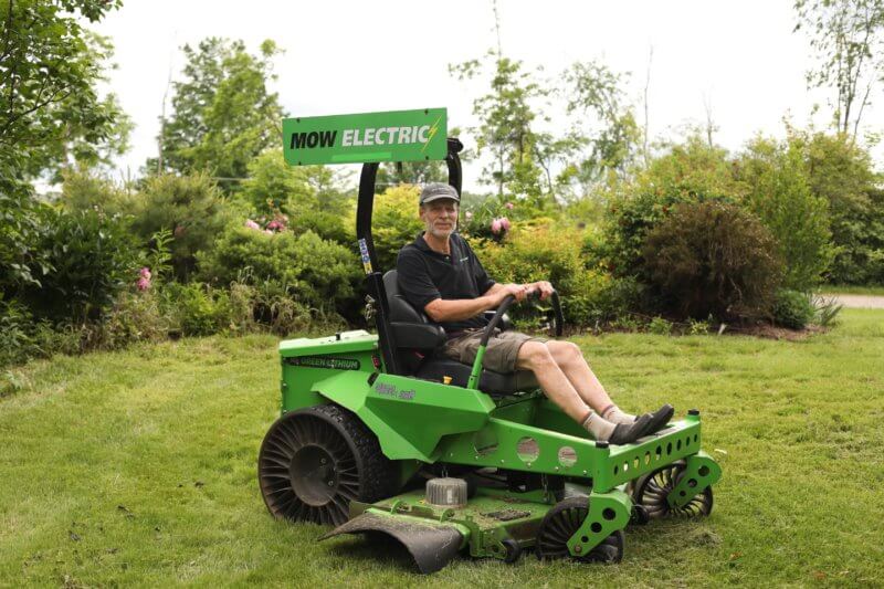 Photo by Satchel Blood Steven Wisbaum, founder of the Mow Electric! campaign, mowing with the Ten Stones Village Association’s Mean Green battery electric zero-turn “commercial” lawn mower.