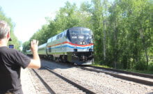 Photo by Scooter MacMillan Rich Ahrens records video of the first passenger train through Charlotte in 70 years and waves as the engineer waves back.