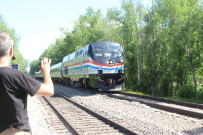Photo by Scooter MacMillan Rich Ahrens records video of the first passenger train through Charlotte in 70 years and waves as the engineer waves back.