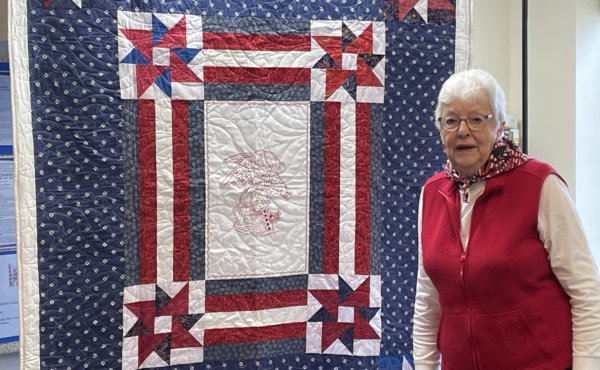 Photo by Lori York. Ruth Whitaker of Shelburne stands with a quilt created by members of Quilts of Valor, whose mission is to cover service members and veterans touched by war with quilts.