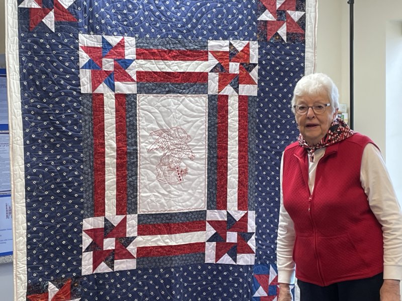 Photo by Lori York. Ruth Whitaker of Shelburne stands with a quilt created by members of Quilts of Valor, whose mission is to cover service members and veterans touched by war with quilts.