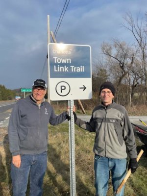 Photo by Larry Sommers Larry Sommers, left, and David Ziegelman stand next to one of the many signs they worked many hours on over the past year to help upgrade signs on Charlotte’s trail system.