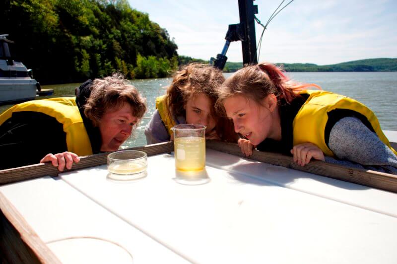 Photo by Ashley EatonA teacher and her students examine a phytoplankton sample aboard the University of Vermont research vessel on Lake Champlain.