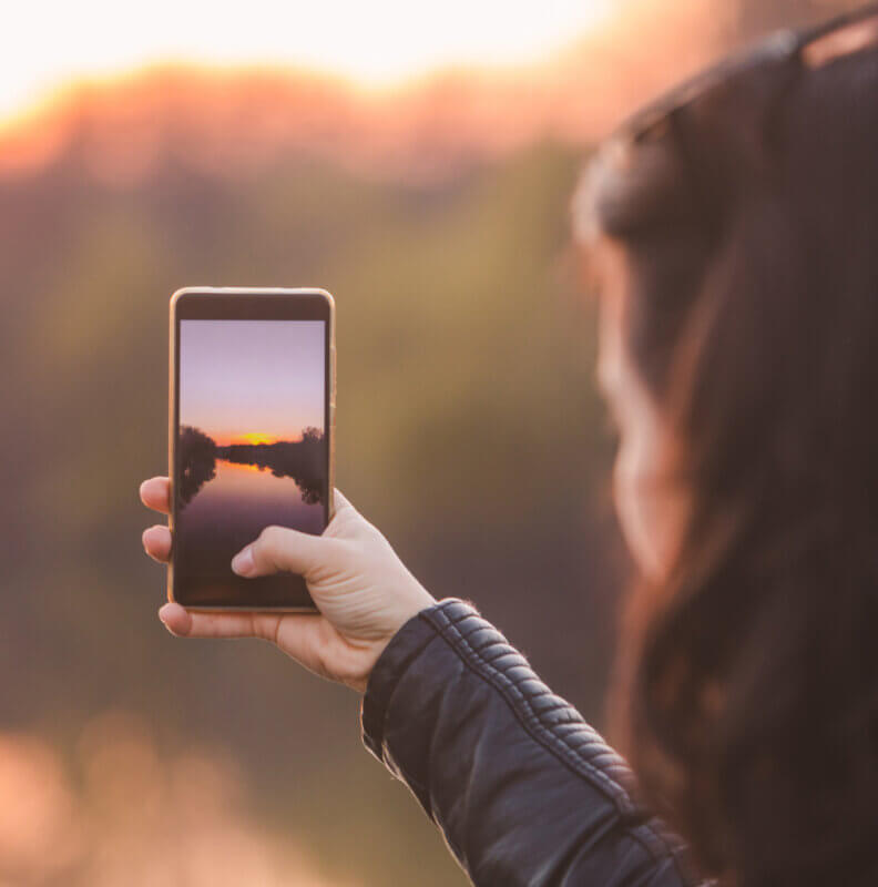 woman taking picture of sunset on her phone. lifestyle concept