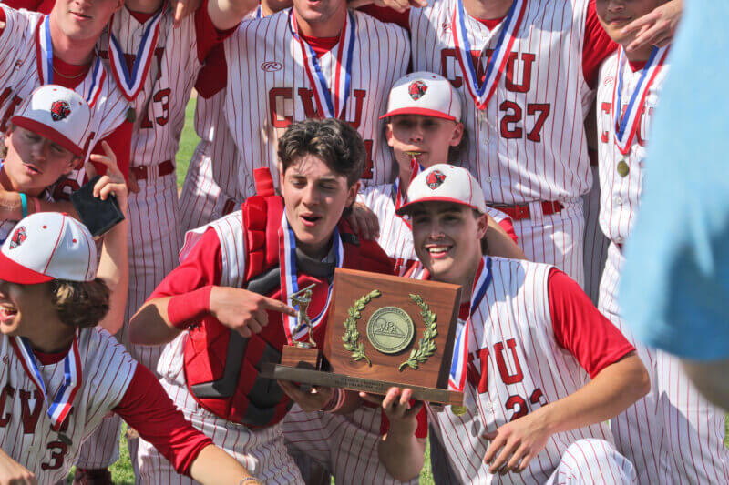 From left, Calvin Steele, Aaron LaRose and Steve Rickert celebrate with CVU’s new trophy after the Redhawks shut out the Patriots 6-0 for the state title.