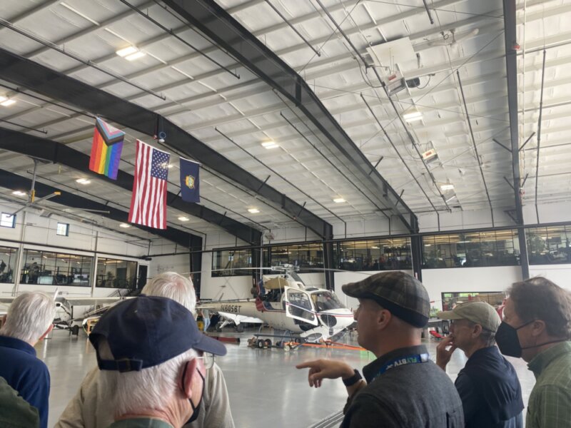 Tyler Seeholzer of BETA Technologies (center) explains the electric commercial aircraft breakthroughs the company is working on to a group of men who regularly gather for breakfast at the Charlotte Senior Center.