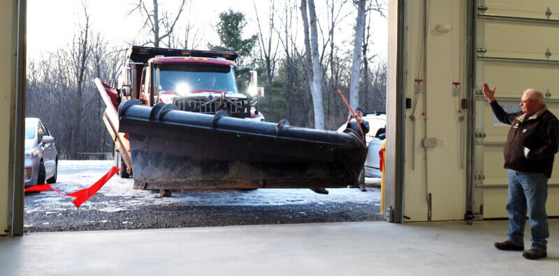 Photo by Lee Krohn. Highway commissioner Junior Lewis 'cuts' the ribbon with his snowplow at the town garage opening ceremony on Wednesday, Nov. 29, while project manager John Kerr celebrates from the sideline.