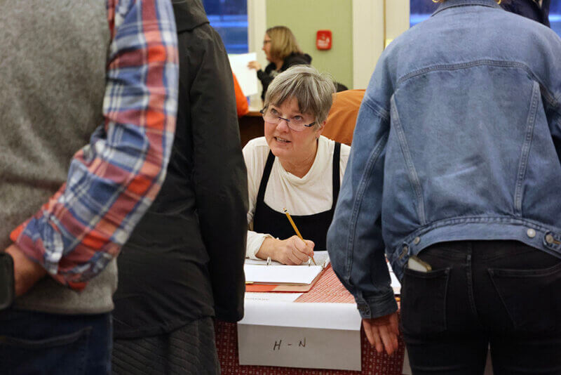 Photo by Catherine Morrissey. Dee Hodson gives instructions to a voter at Charlotte’s Town Hall on Town Meeting Day.