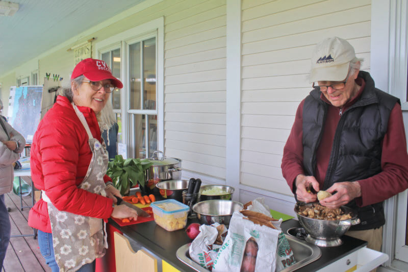 Library director Margaret Woodrum and Wolfger Schneider of the Charlotte Energy Committee cut up cleaned veggies and ramps for Disco Soup, a Slow Food demonstration of ways food waste reduction can help with the climate crisis.