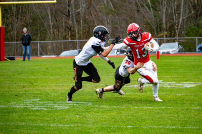 George Taylor fights off a pair of would-be tacklers in Champlain Valley's 21-7 win over Middlebury in the second round of the state championship.