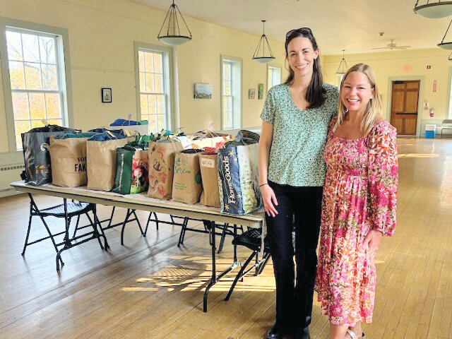 Picture by Peggy Sharpe.
From left, Alicia Cooper and Katie Shearer stand ready to distribute winter clothes collected for food shelf families.