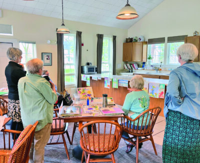 Photo by Lori York. Students reflect on their watercolor paintings with instructor Lynn Cummings.