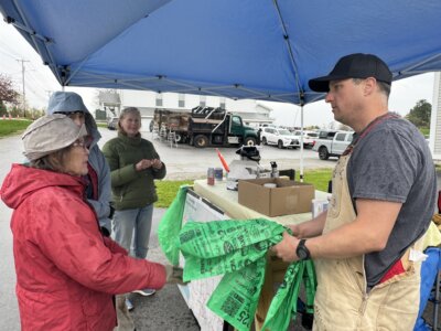 Photo by Scooter MacMillan. Nancy Wood, left, dispensed green bags and kept up with which roads had been picked up and which hadn’t. Steve Schubart, who came to get bags, said he had been picking up trash for Green Up Day since he was old enough to do so.