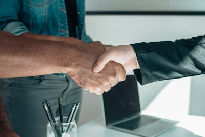 Two individuals engaging in a professional handshake in a modern office environment.