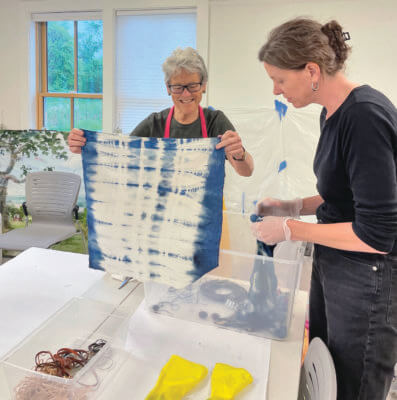 Photos by Susanna Kahn. Left: Toby Goldsmith mixing up indigo dye for participants. Right: Lynne Bond and Brittany Slabaugh reveal their indigo creations.
