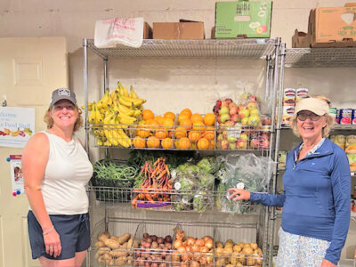 Photo by Peggy Sharpe. From left, Charlotte Food Shelf volunteers Michelle Donlon, Liz Foster and new shelving filled with fresh vegetables at the Charlotte Food Shelf.