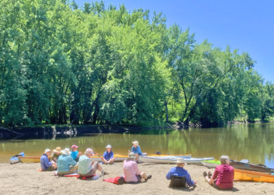 Photo by Jean Rook. Kayakers pause along the shores of Otter Creek to enjoy a water break and some conversation.