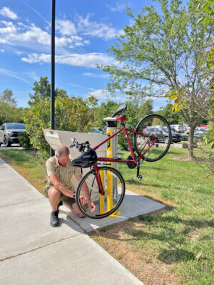 Photo by Susanna Kahn. Matt Bijur demonstrates how to use the new bike repair station in the library parking lot.